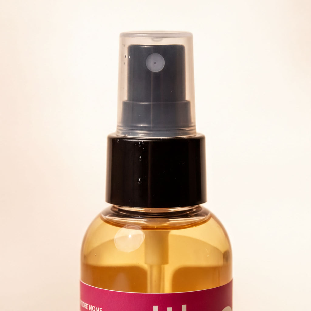 A spray bottle with a black cap and a pink label.