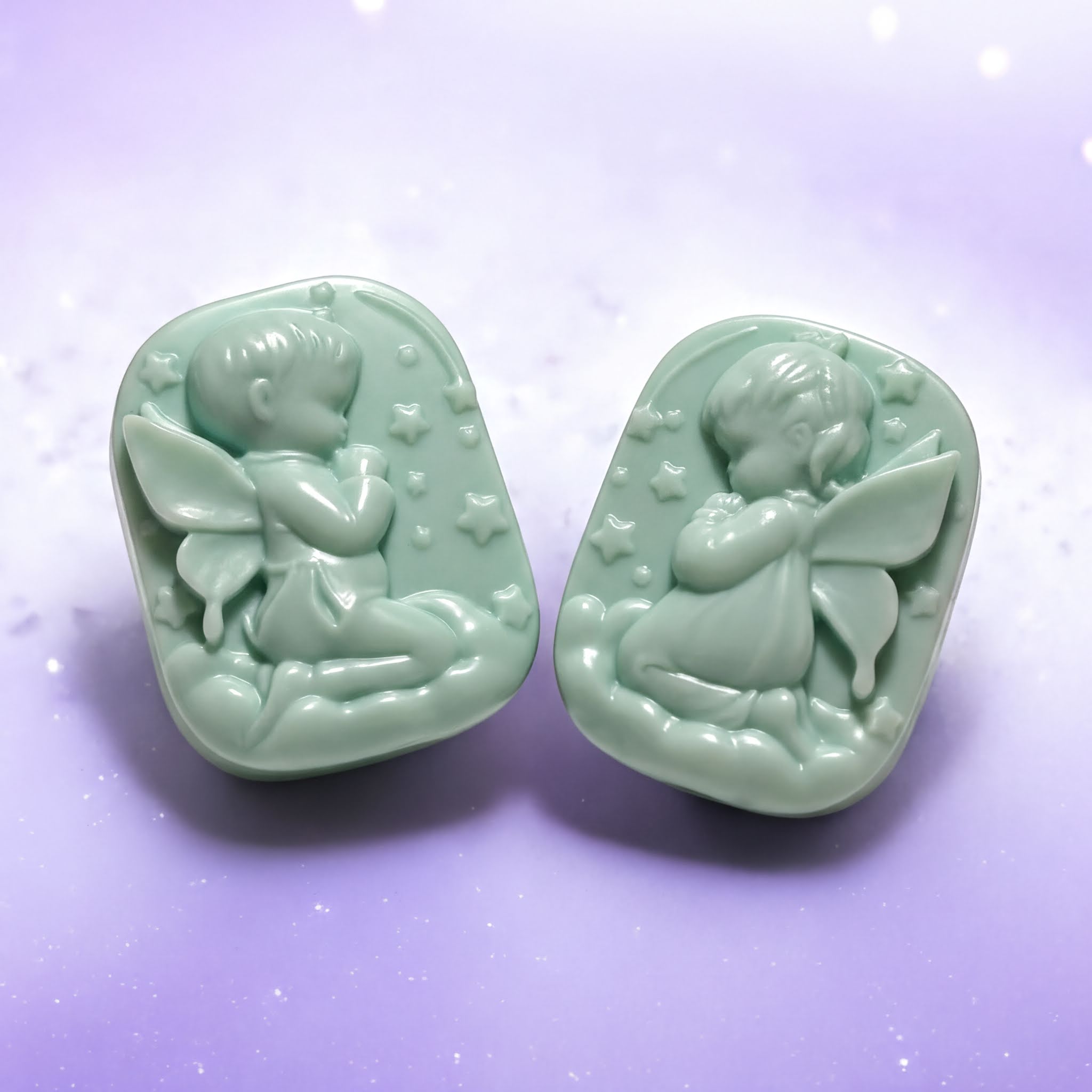 Two green soapstone charms depicting angelic figures are shown against a purple background.