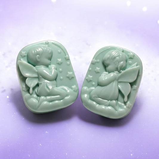 Two green soapstone charms depicting angelic figures are shown against a purple background.