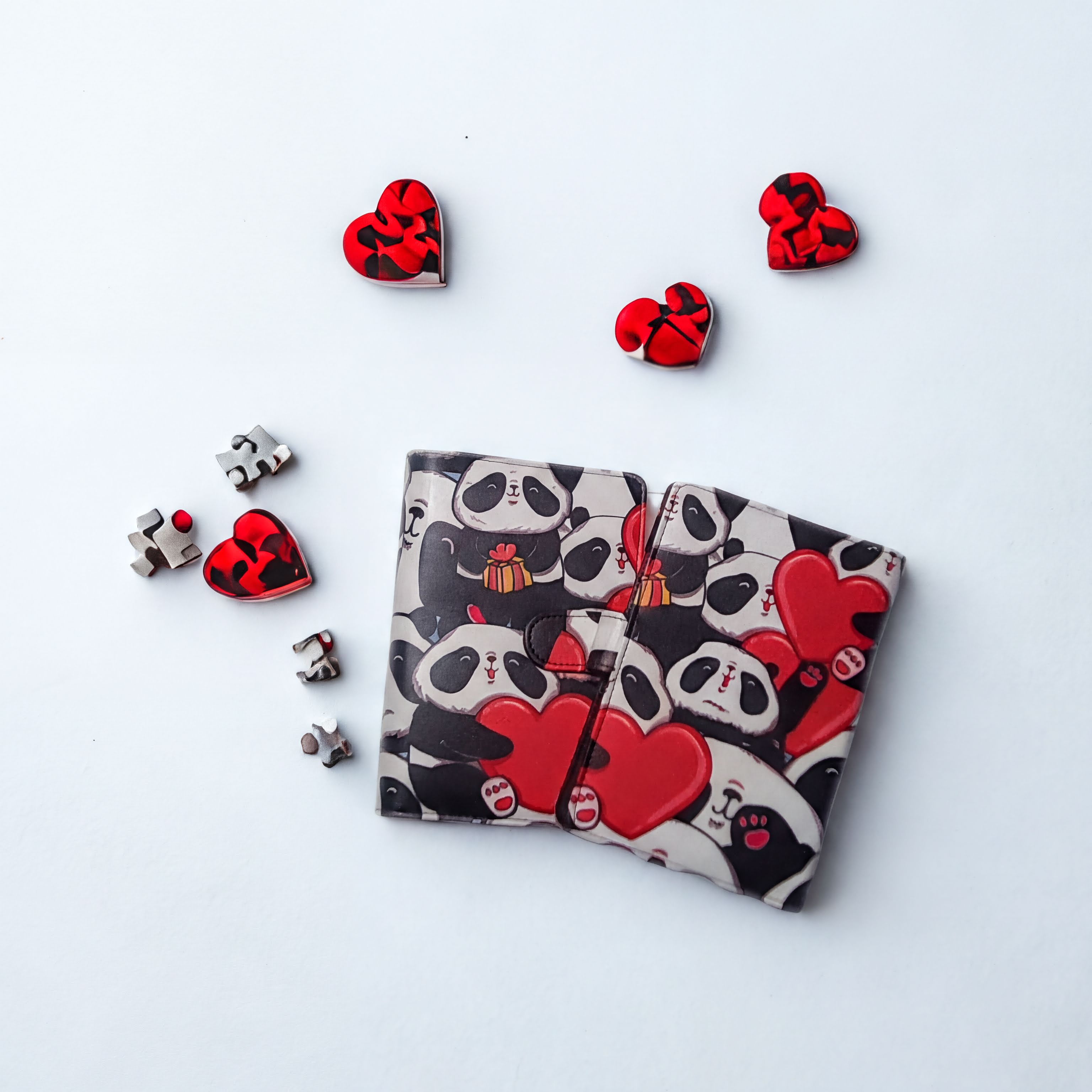 Cute panda wallet with red hearts, surrounded by heart-shaped puzzle pieces on white background