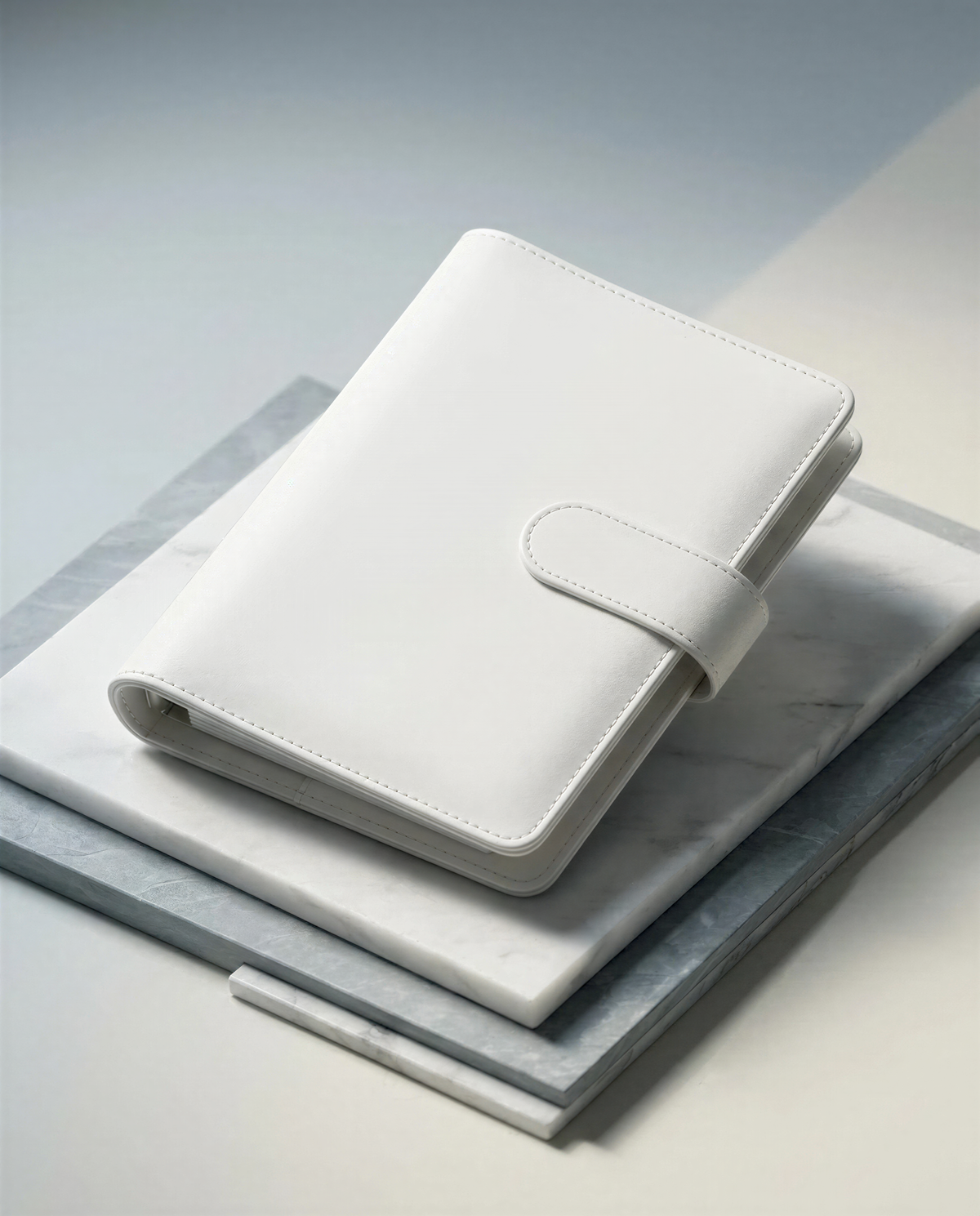 A white leather wallet or book is resting on a marble surface.