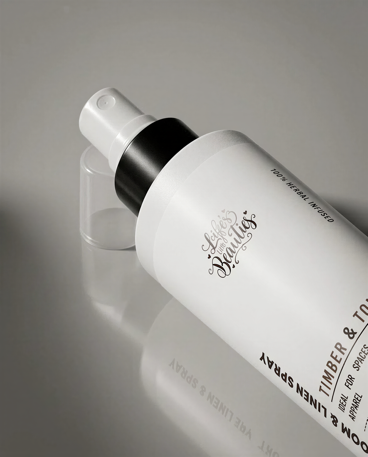 A spray bottle with a black cap and white label, resting on a reflective surface.
