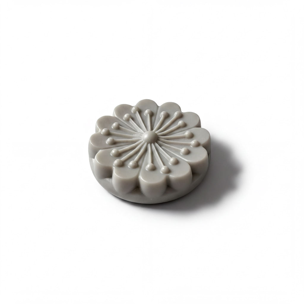 A gray, flower-shaped object with a central design and radiating petals is shown against a white background.