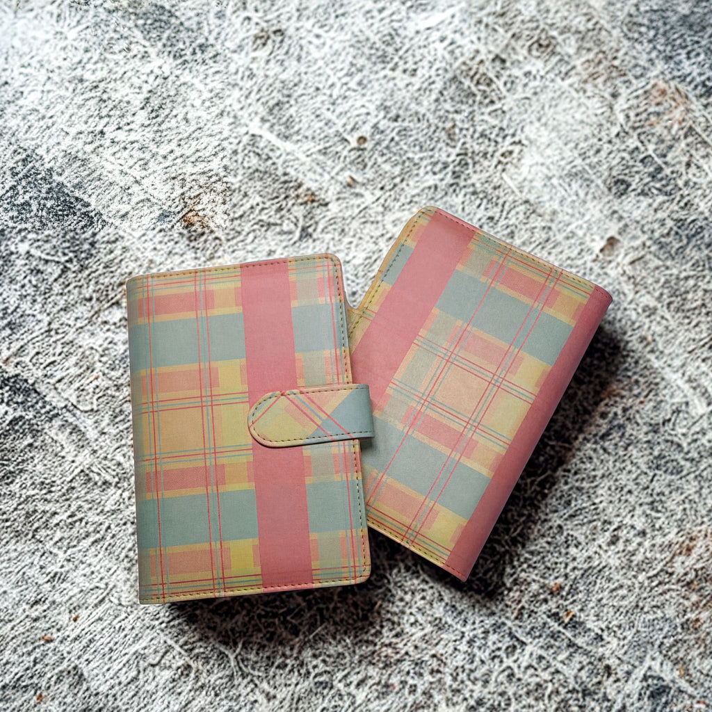 Plaid-patterned wallet with pink, yellow, and blue tones on textured surface