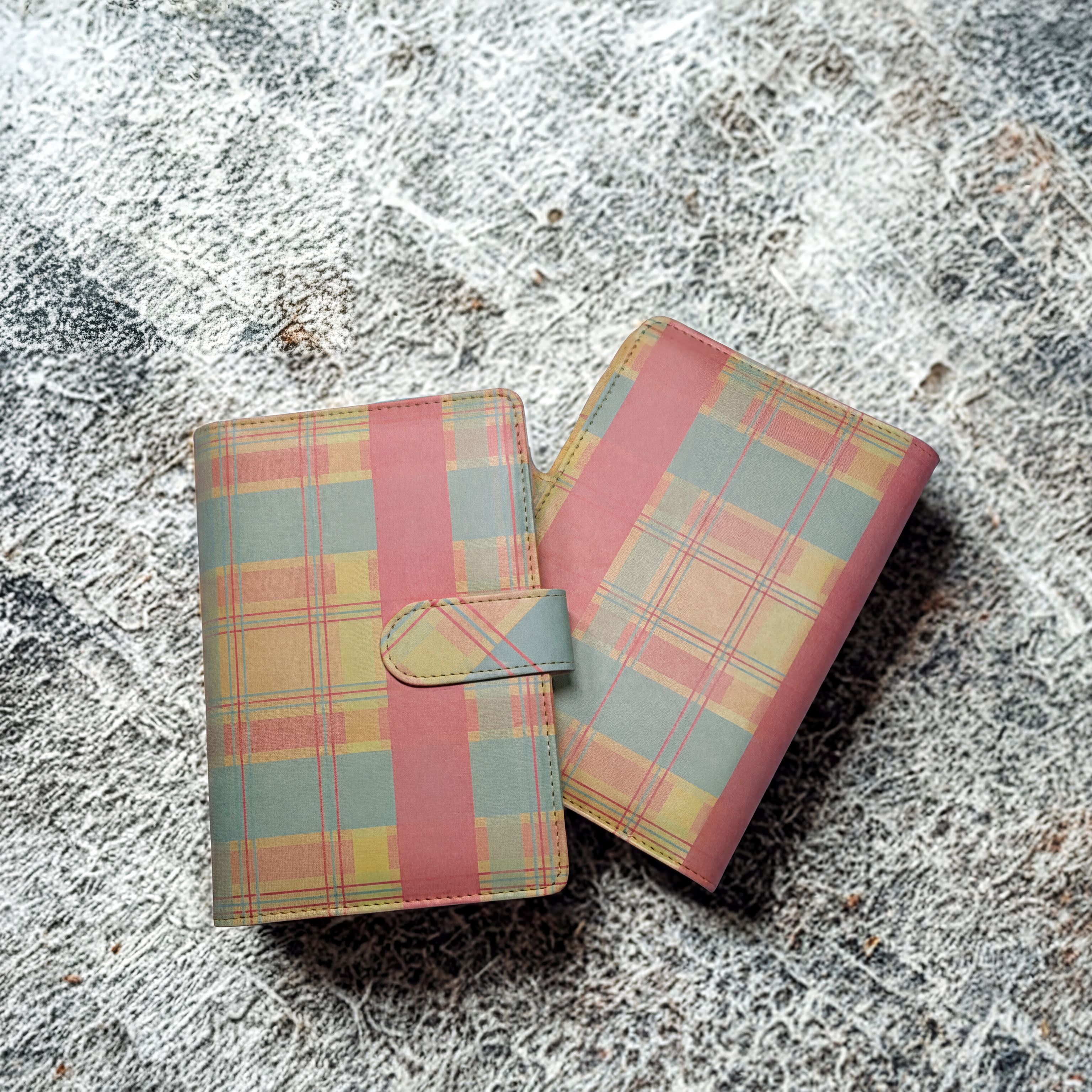 Plaid-patterned wallet with pink, yellow, and blue tones on textured surface