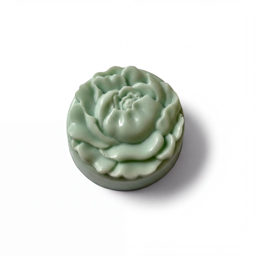 A green, flower-shaped soap bar is shown against a white background.