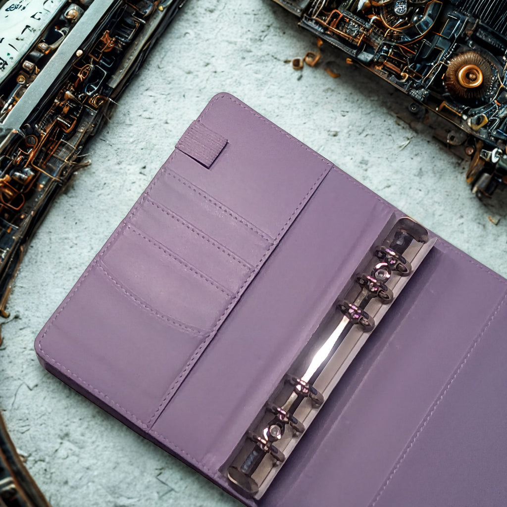 Purple leather planner with metal rings and card slots on concrete surface