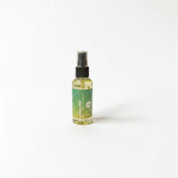 A bottle of liquid with a green label is standing upright on a white background.