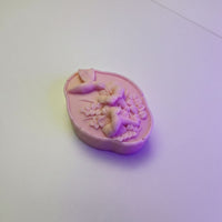 A pink soap bar with a floral design on it, sitting on a white surface.