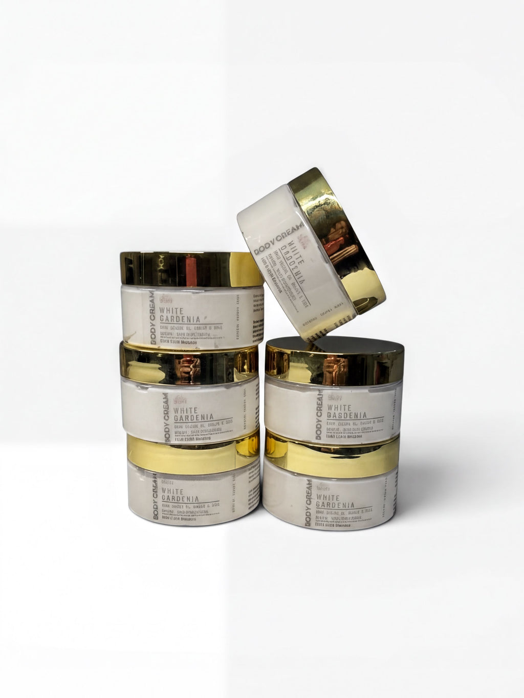A stack of six jars of "White Gardenia" skincare product, with gold-colored lids, against a white background.