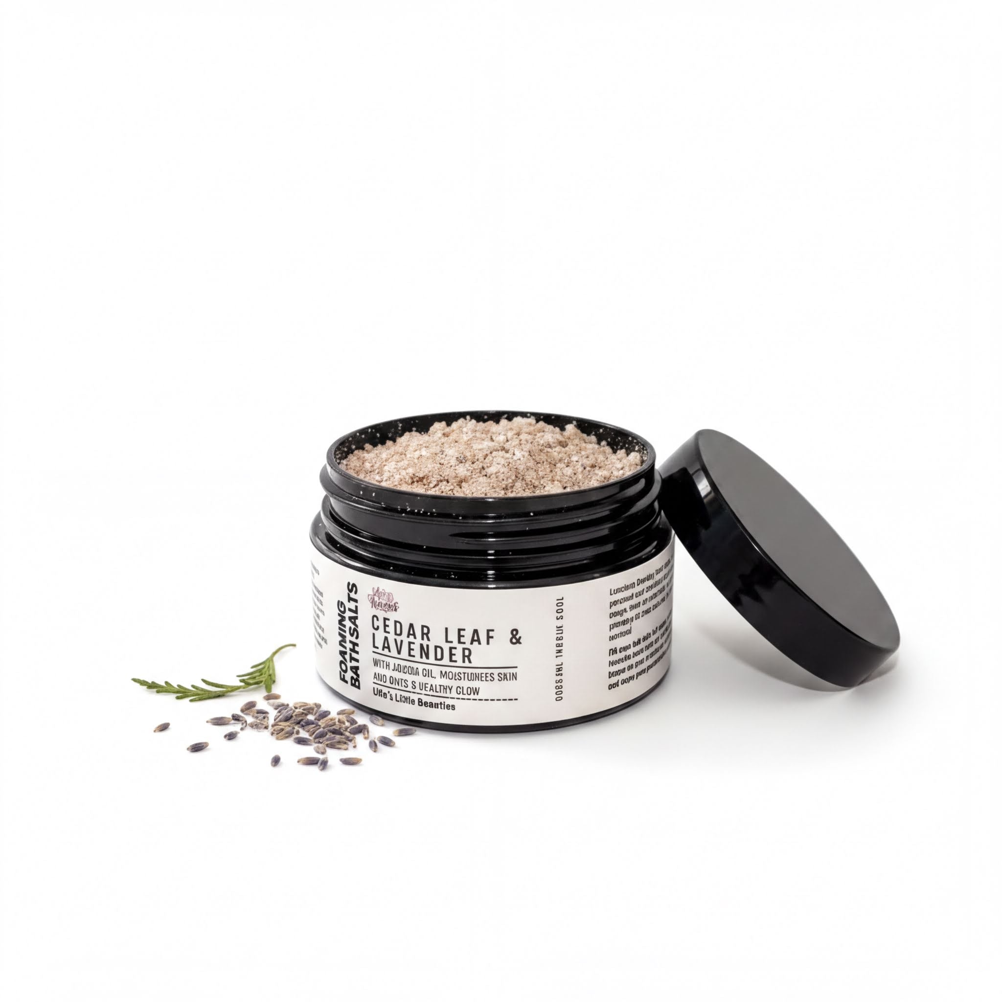 A jar of bath salt with a black lid, containing a mixture of brown and white grains, and a sprig of lavender.