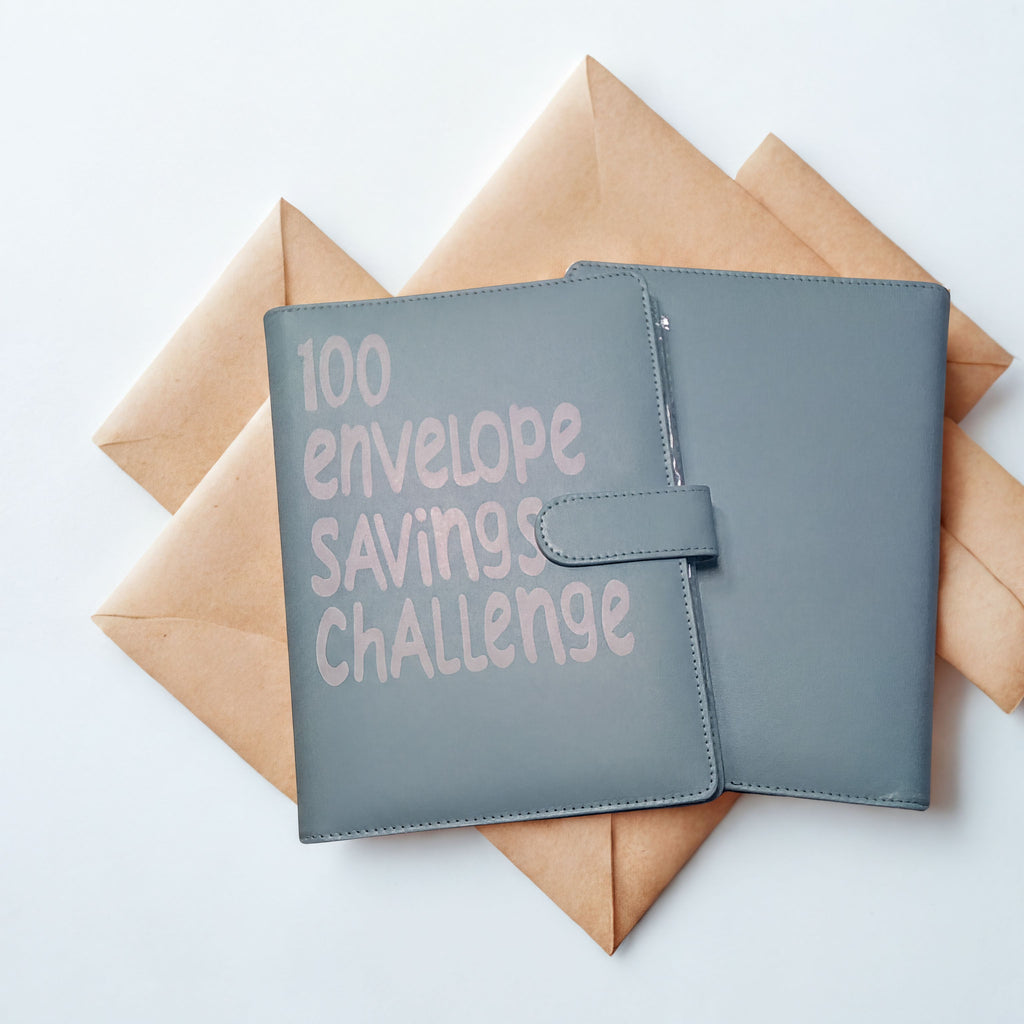 Gray leather 100 envelope savings challenge tracker with brown paper envelopes on white background
