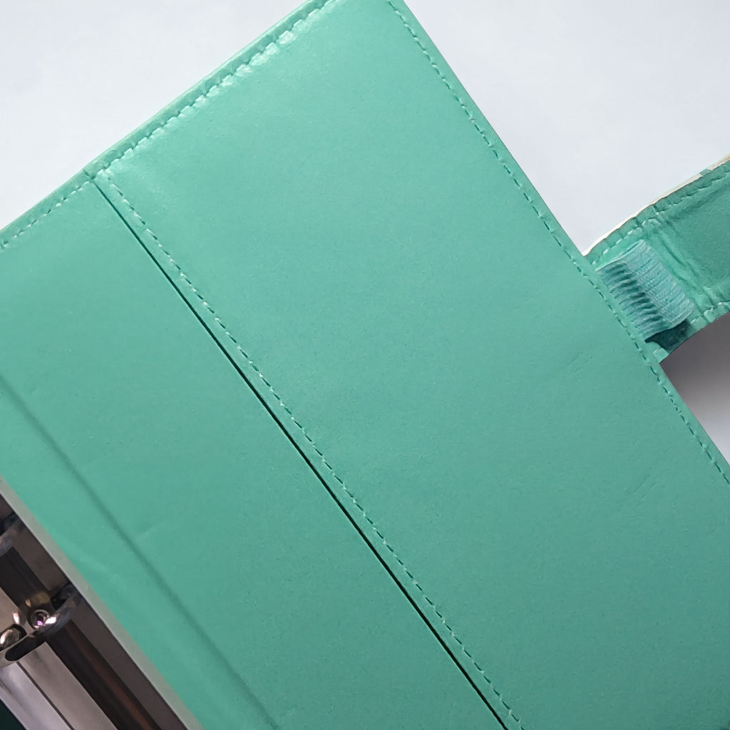 Mint green leather-bound journal with visible stitching and metal clasp detail