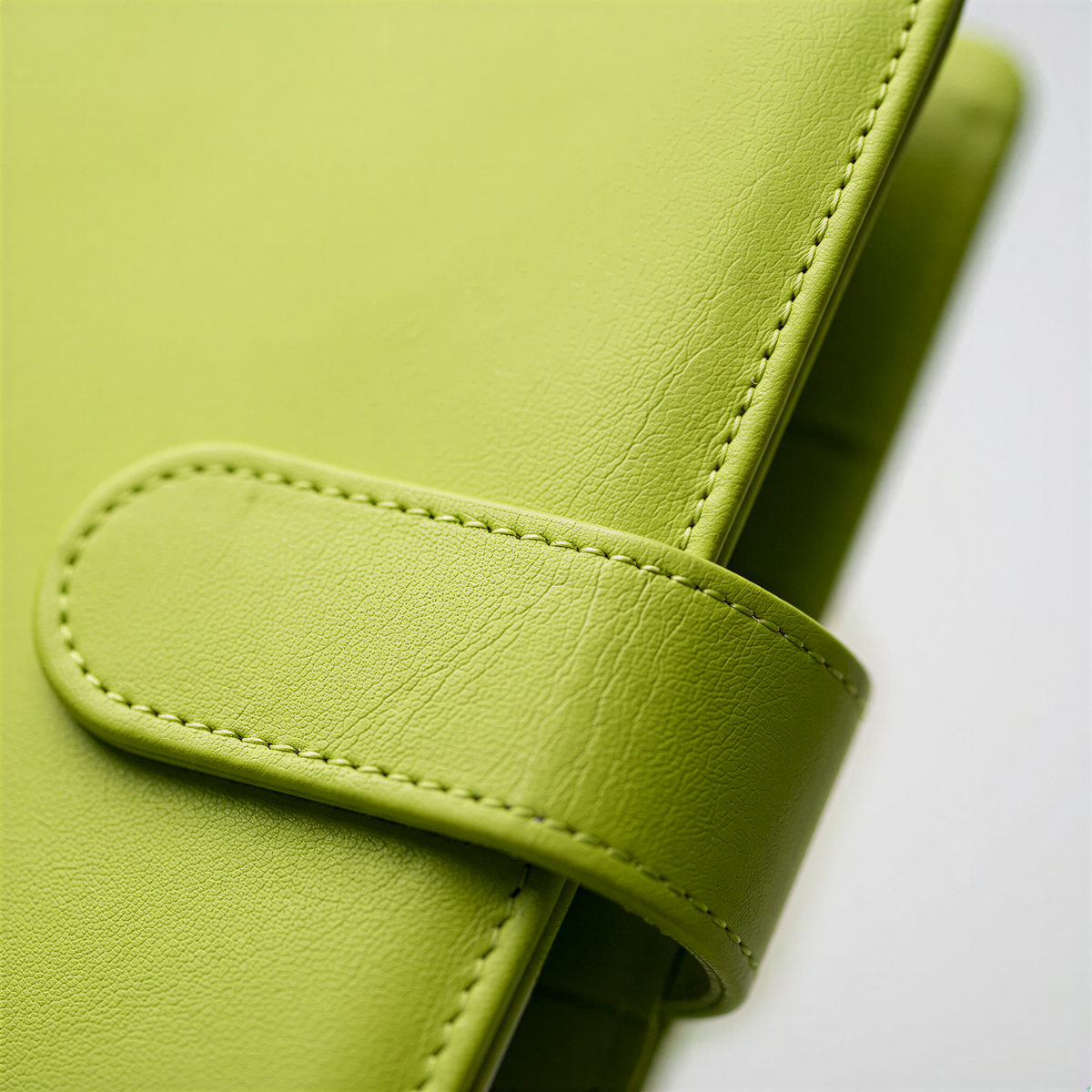 A close-up view of a bright green leather wallet or pouch, with a small zipper or clasp visible.
