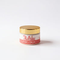 A jar of body cream with a gold lid and a pink label.
