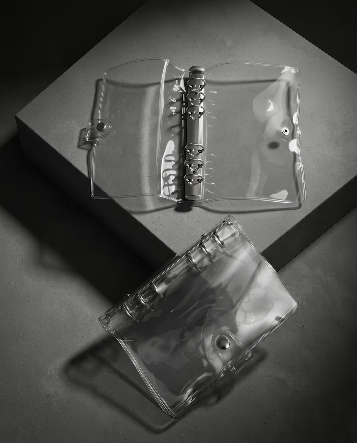 A transparent plastic binder with a metal ring mechanism, placed on a gray surface.