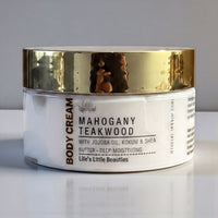 A jar of Mahogany Teakwood body cream with jojoba oil, kokum, and shea butter, with a gold lid.