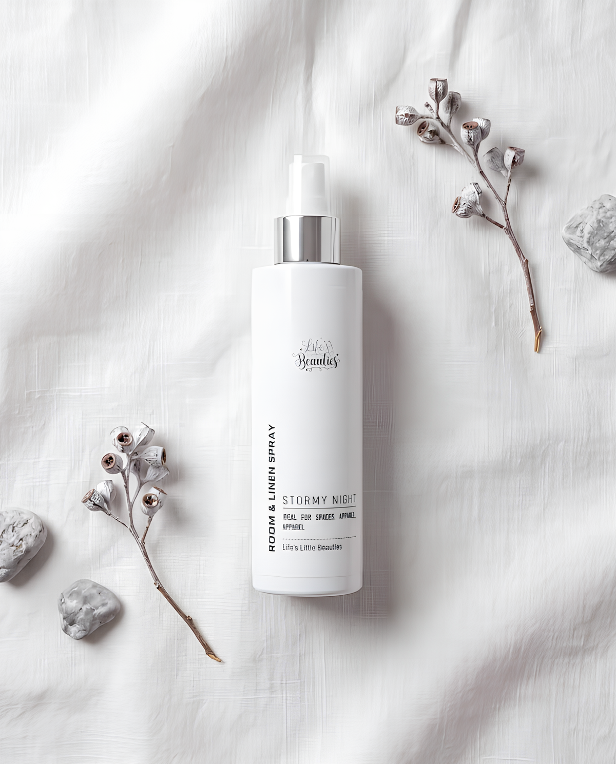 a bottle of "Stormy Night" linen spray placed on a white background, surrounded by small branches and rocks.