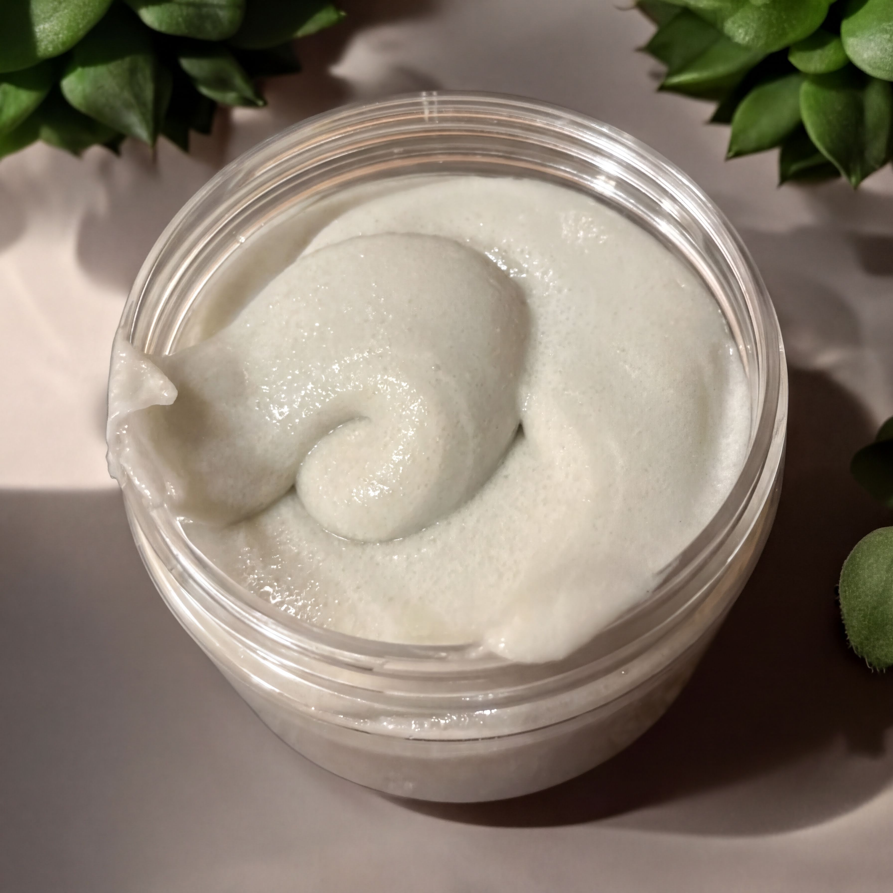 A clear jar containing a white, creamy substance, possibly a lotion or cream, with a swirled or curled shape.