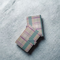 Two plaid wallets are placed on a textured surface.
