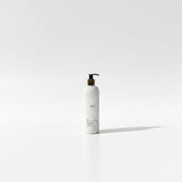 A white pump bottle with a black pump and label stands alone against a plain white background.