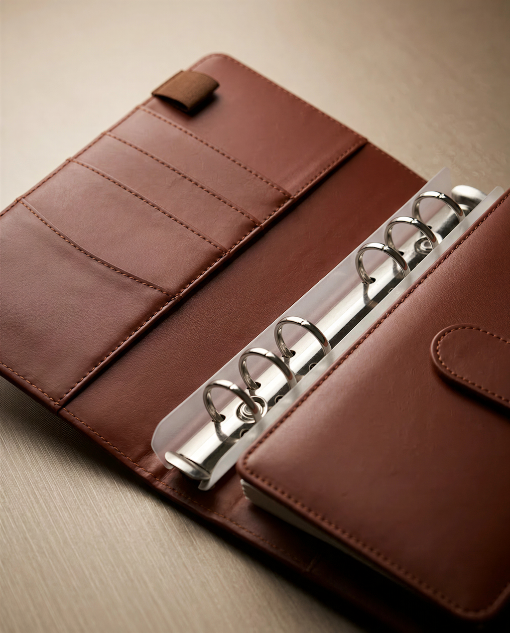 A brown leather-bound spiral notebook with a metal ring mechanism, placed on a wooden surface.