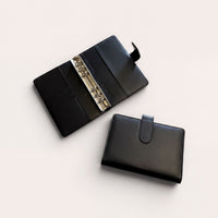 a black leather wallet and a binder with rings, both placed on a white background.