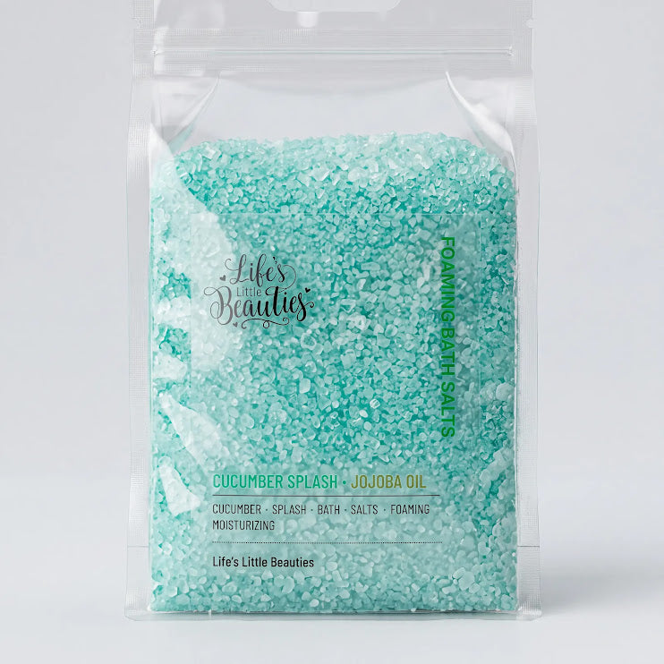 A clear plastic bag filled with turquoise-colored bath salt crystals, labeled as cucumber splash, jojoba oil, and containing various ingredients such as cucumber, splash, bath, salt, and foaming.
