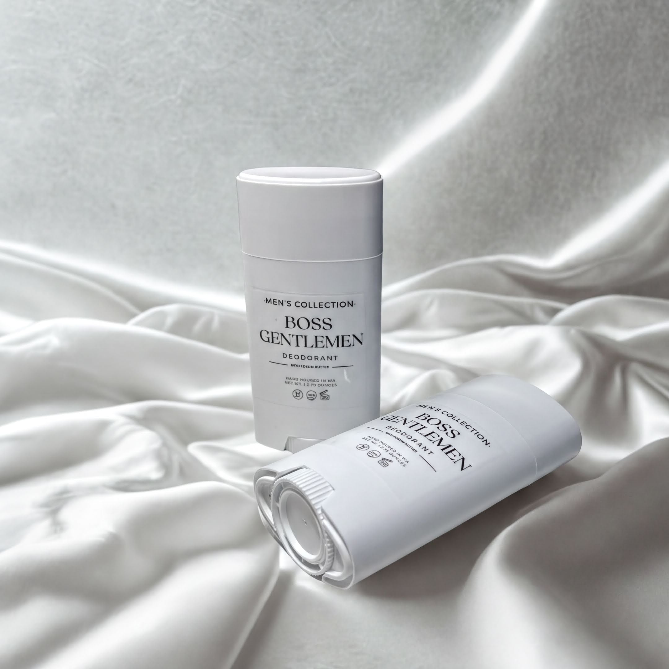 Two white deodorant sticks are placed on a white fabric background.