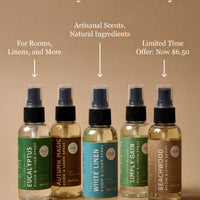 five bottles of room sprays, each with a different scent, arranged in a row against a beige background.