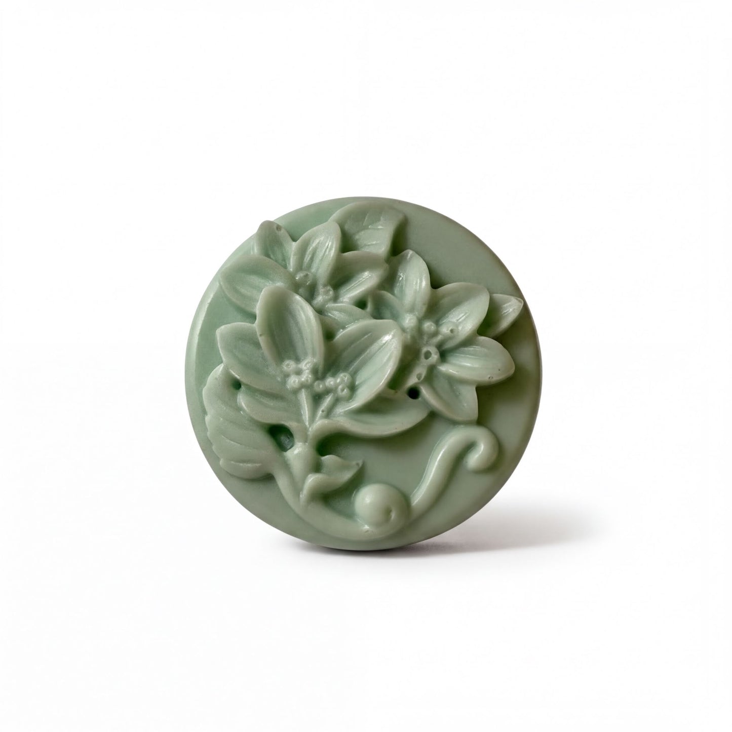 A round, green soap dish with a floral design featuring leaves and flowers.