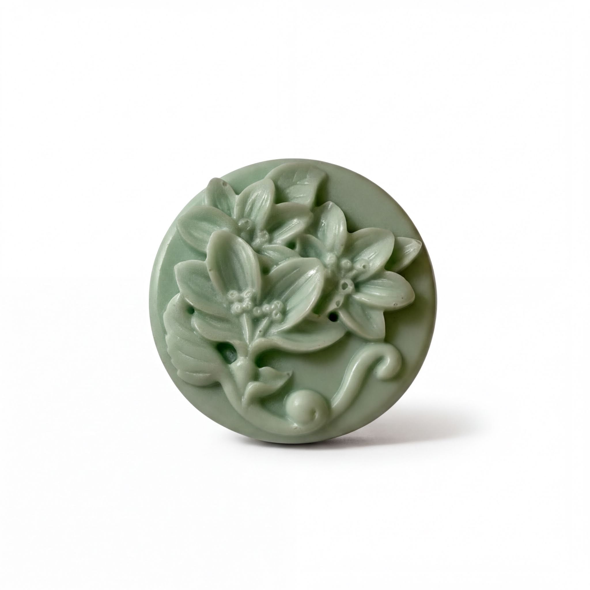 A round, green soap dish with a floral design featuring leaves and flowers.