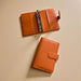 Two leather wallets are placed on a light-colored surface.