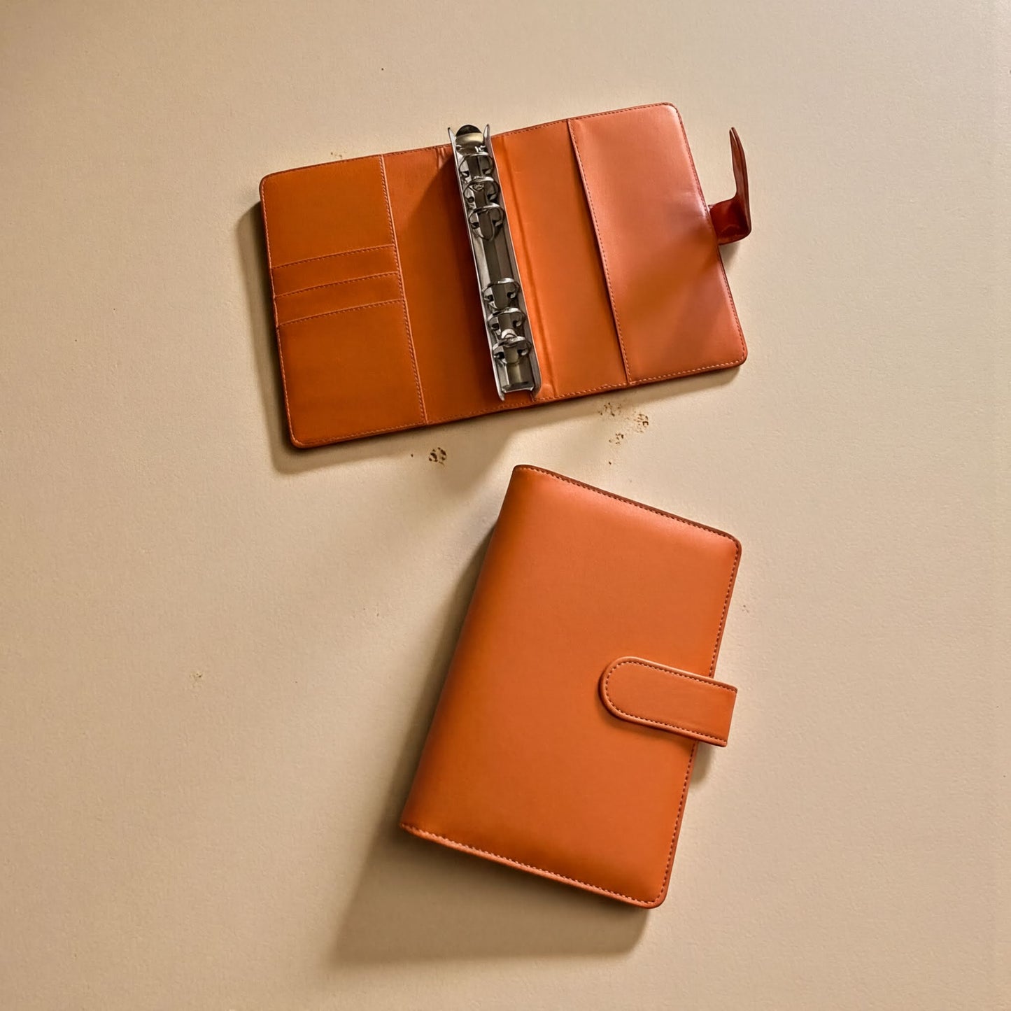 Two leather wallets are placed on a light-colored surface.
