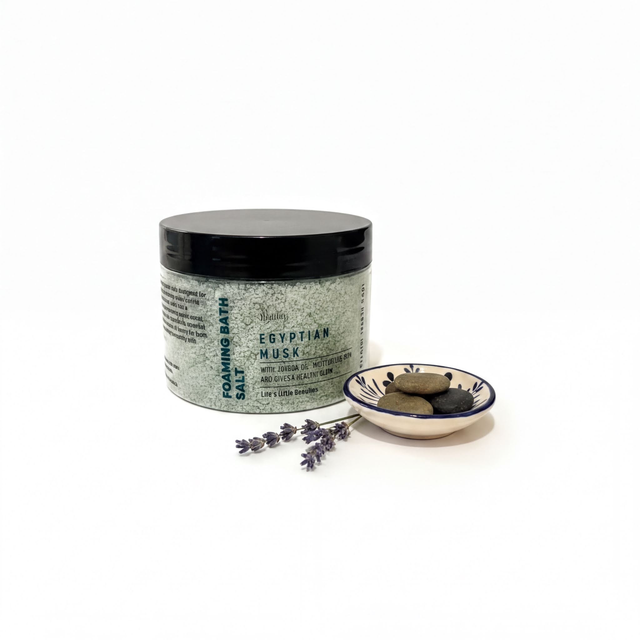 a jar of Egyptian musk salt next to a small bowl containing rocks and lavender flowers.