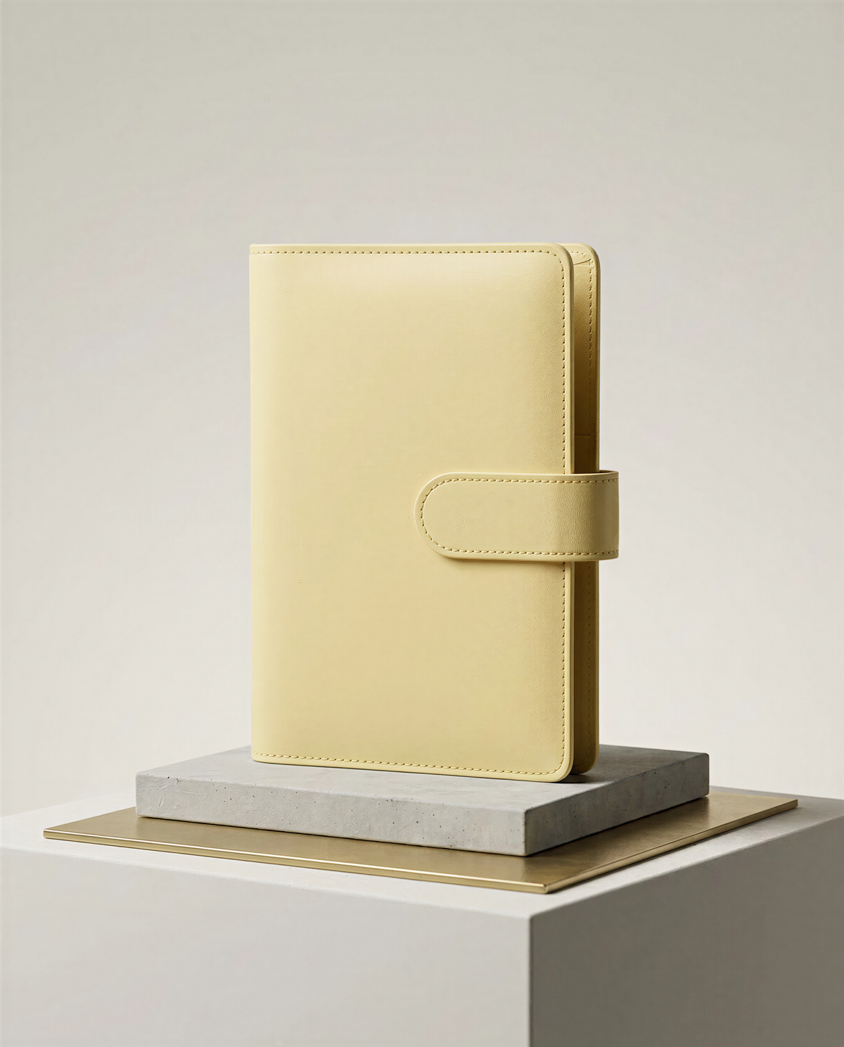 A yellow leather-bound notebook or planner is displayed on a white pedestal against a plain white background.