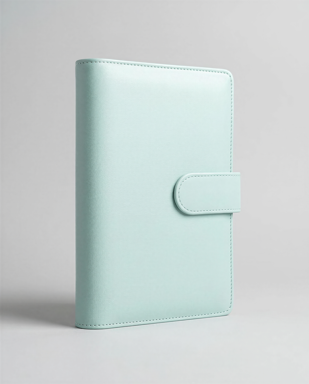 A mint green leather wallet or book cover is shown against a plain background.