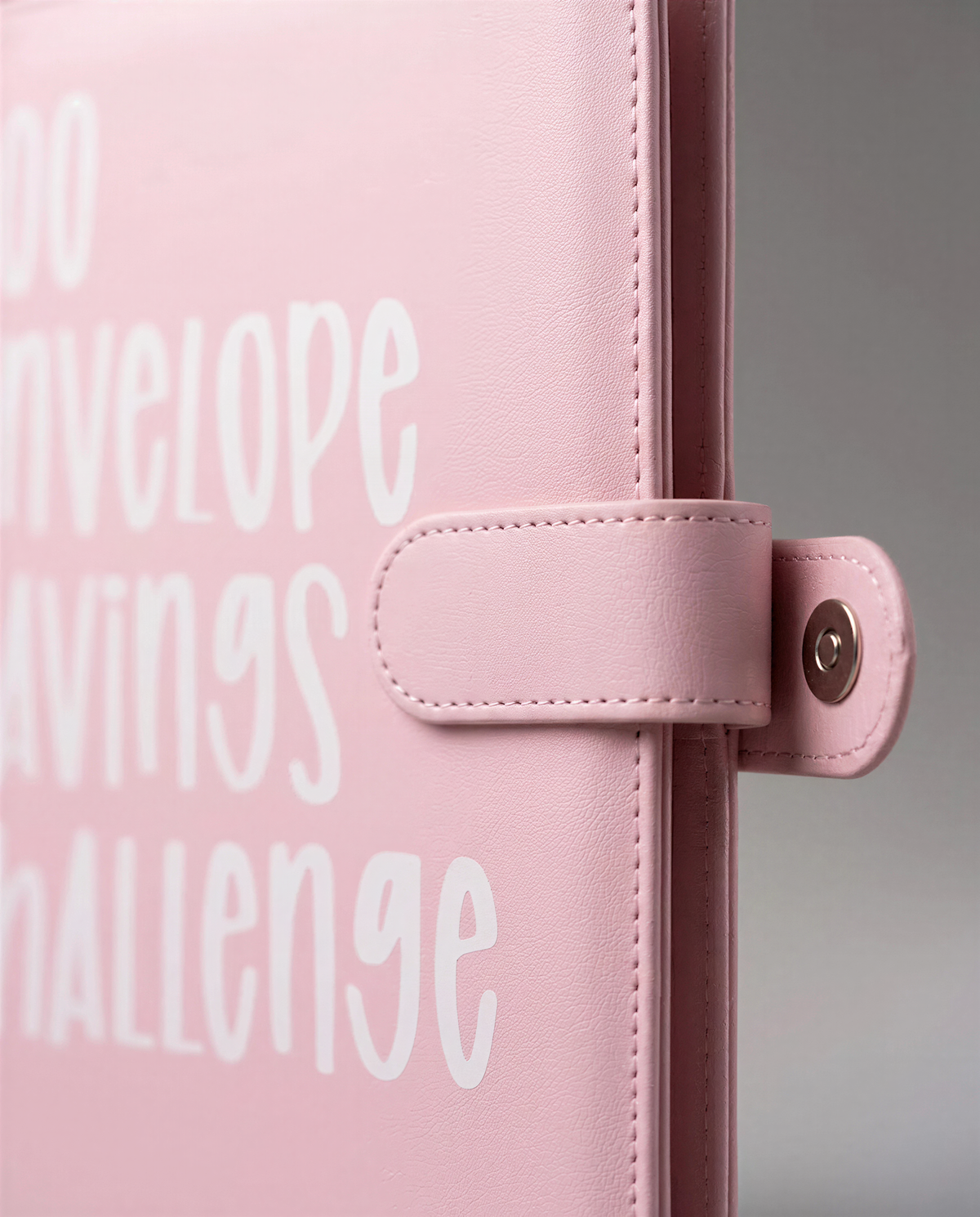 A pink leather-bound notebook or binder with the text "SAVINGS CHALLENGE" printed on it.