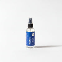 A clear bottle with a blue label that reads "THE OMEGA Lotion 100% ORGANIC OIL".