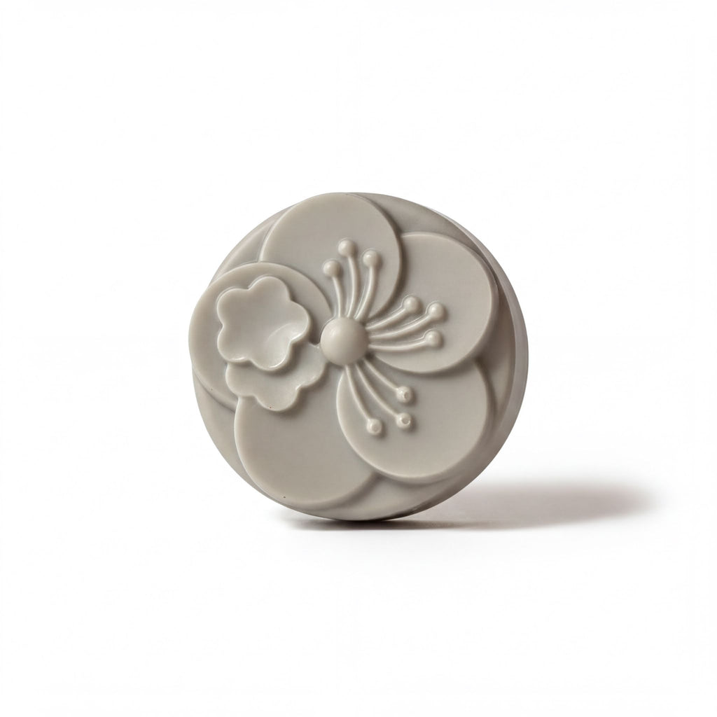 A gray, circular soap with a flower design on it.