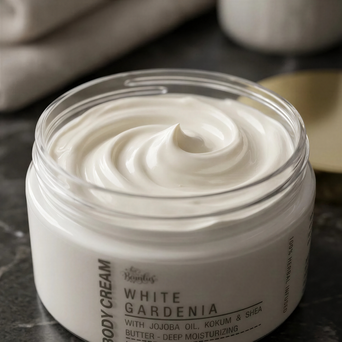 A jar of white gardenia body cream with jojoba oil, kokum, and shea butter, placed on a marble countertop.