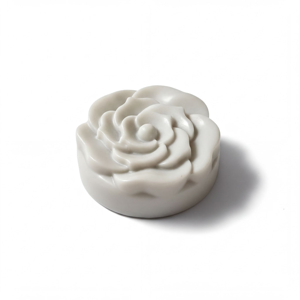 A white, round soap-like object with a flower-like design on it, sitting on a white background.