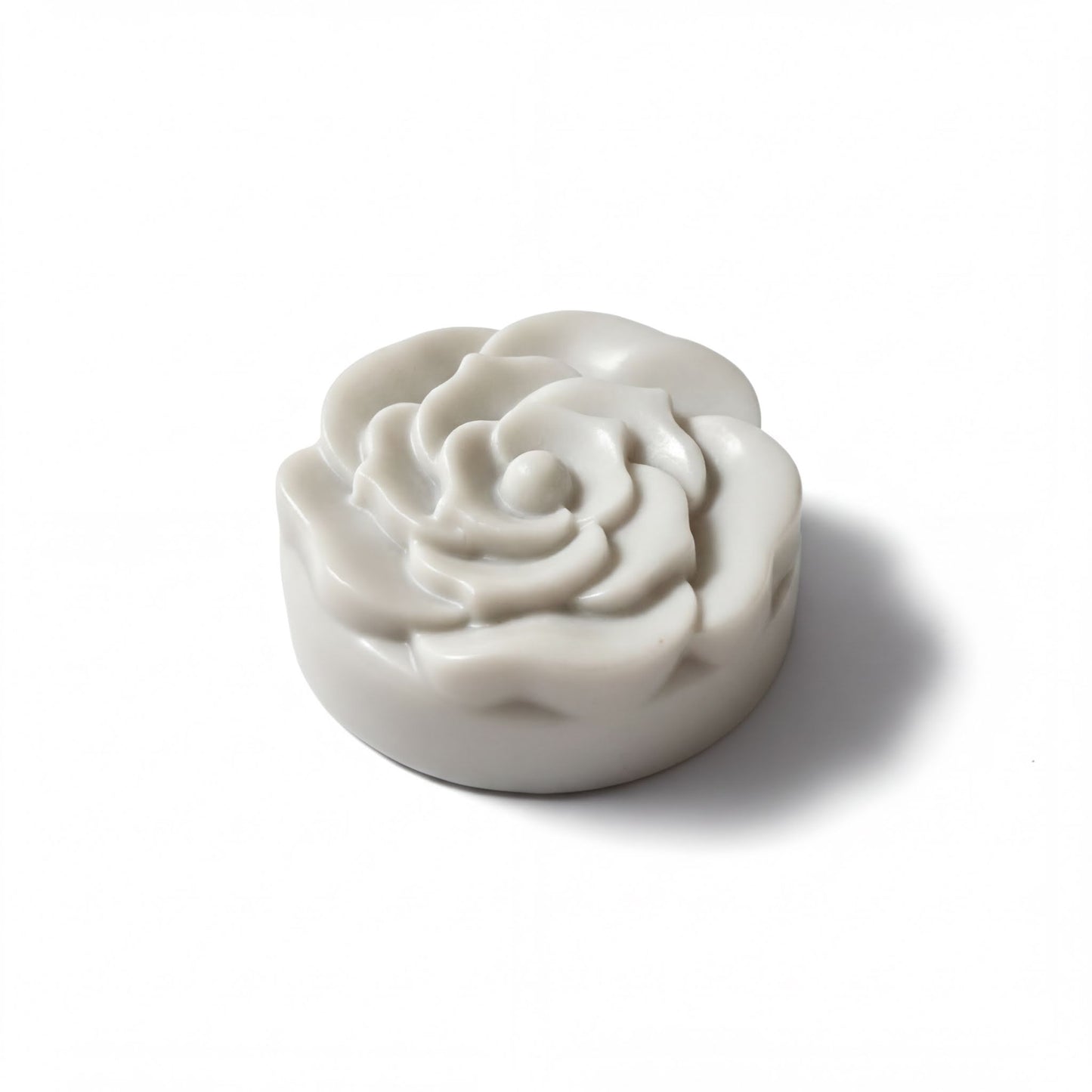 A white, round soap-like object with a flower-like design on it, sitting on a white background.