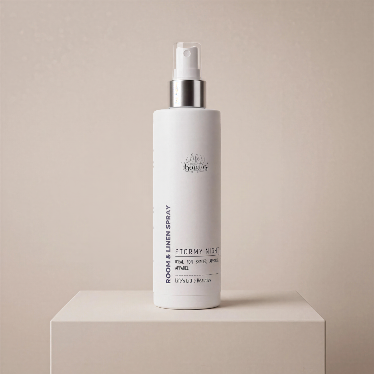 A bottle of "LESS THAN 500" room and linen spray is standing on a white pedestal against a light beige background.
